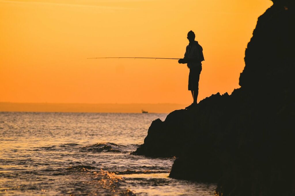 Mann angelt in der Abendsonne am Meer in Griechenland