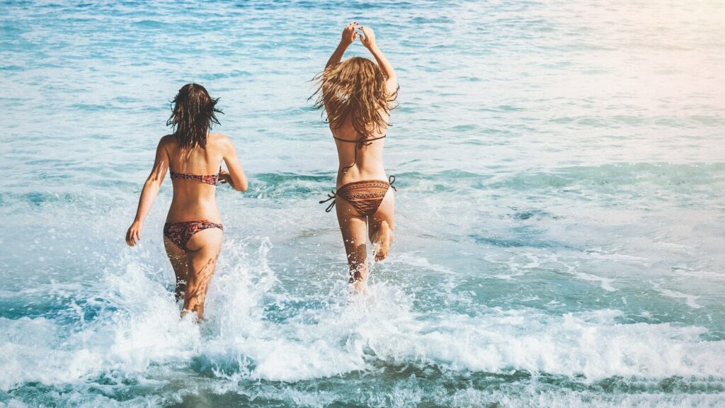 Auf Schnäppchenjagd & auf der suche nach einer günstigen Pauschalreise rennen zwei schöne Frauen unbeschwert ins strahlend blaue Meer